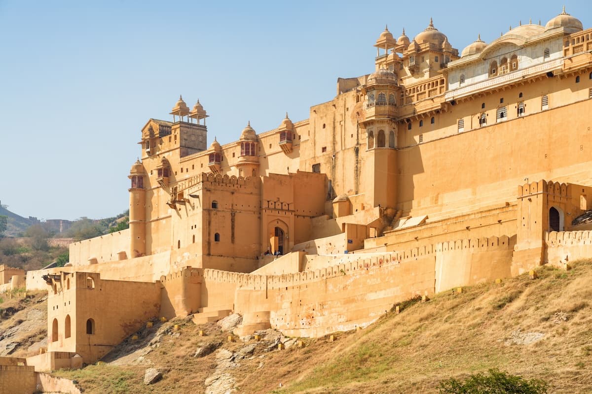 Amer Fort over Maota-søen nær Jaipur i Rajasthan — sandstensmure, terrasserede gårde og Aravalli-udløbere.